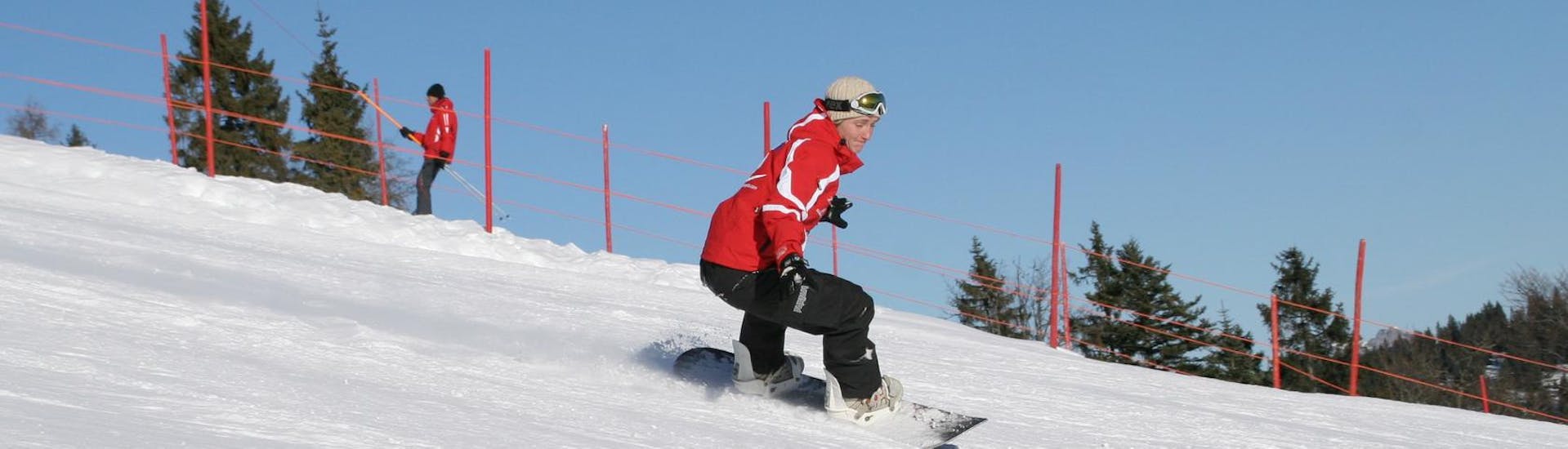 Un snowboarder dévale les pistes pendant ses cours particuliers de snowboard pour enfants et adultes de tous niveaux avec l'école de ski Busslehner.