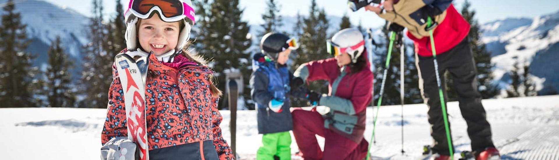 Zwei Eltern helfen ihren Kindern bei der Vorbereitung auf den privaten Kinder-Skikurs aller Altersgruppen in der Snowacademy Saalbach.
