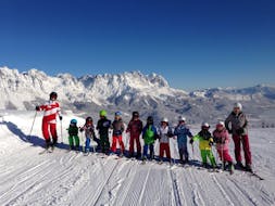 Een groep kinderen bij hun kinderskilessen (3 tot 14 jaar) voor gevorderde skiërs met hun skileraren van de Skischool Ellmau Hartkaiser.