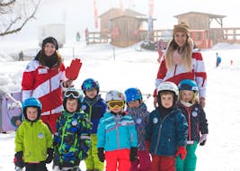 Un grupo de niños en las clases de esquí infantil (de 3 a 14 años) para principiantes con sus monitores de la Escuela de Esquí Hartkaiser de Ellmau.