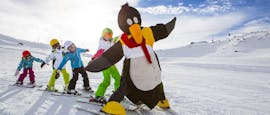 Kinderen vermaken zich met de pinguïn Bobo tijdens de kinderskilessen voor beginners bij skischool Ruhpolding in het Westernberg skigebied.