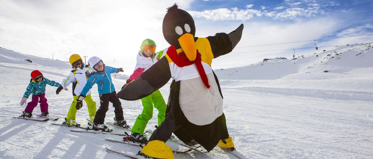 Kids are having fun with the penguin Bobo during the kids ski lessons for beginners with ski school Ruhpolding at the Westernberg ski area.