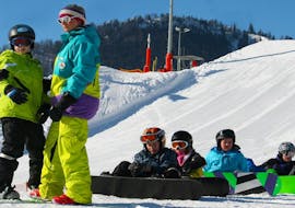 Sommige mensen nemen snowboardlessen voor beginners bij skischool Ruhpolding in het Westernberg skigebied.