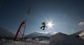 A snowboarder is jumping in the Fun park during snowboarding lessons for advanced snowboarders with ski school Ruhpolding.