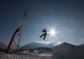 A snowboarder is jumping in the Fun park during snowboarding lessons for advanced snowboarders with ski school Ruhpolding.