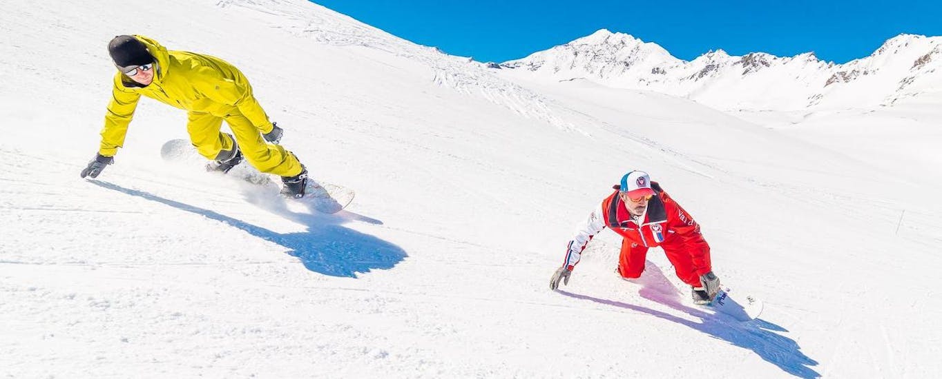 Due snowboarder scendono dalla pista durante le lezioni di snowboard per bambini e adulti - tutti i livelli organizzate dalla scuola ESF Val d'Isère.