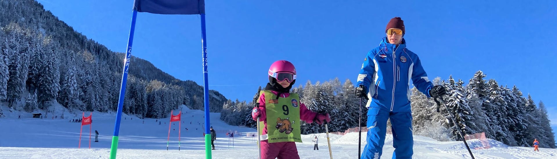 bambina con maestro di sci durante una lezione privata di sci con scuola di sci a Dobbiaco.