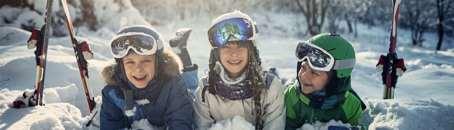 Drie kinderen hebben plezier in de sneeuw tijdens hun skilessen voor kinderen bij skischool Jennerkids TreffAktiv.