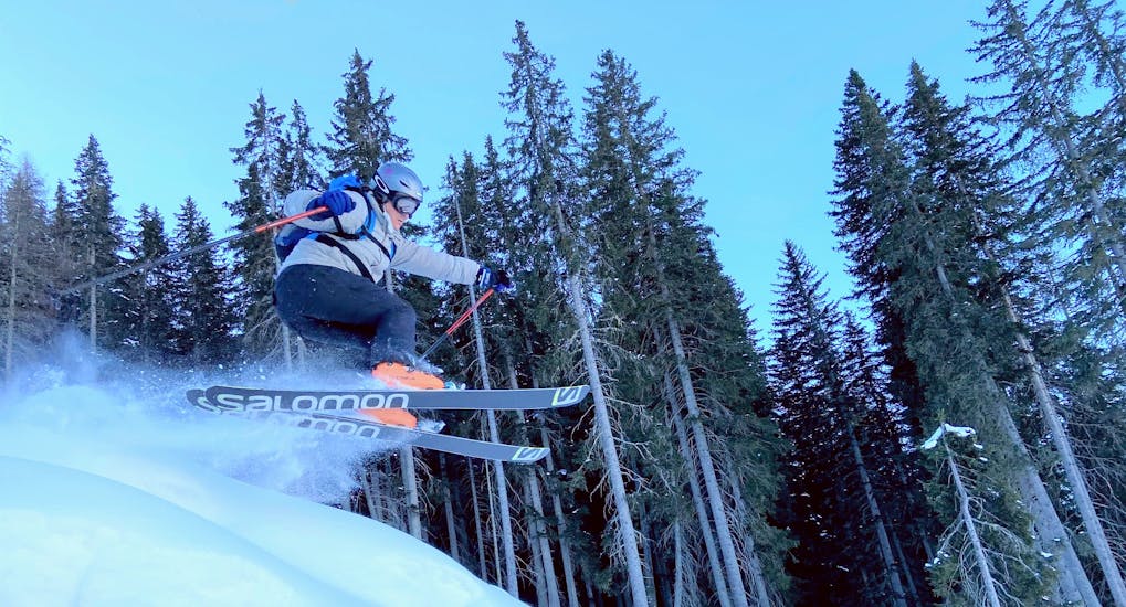 Ein Mann springt mit den Skiern während einer privaten Skistunde für Erwachsene aller Levels mit der Skischule Toblach.