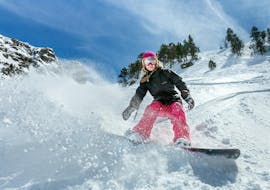 Donna che fa snowboard durante lezione di snowboard per bambini e adulti di tutti i livelli con scuola di sci Dobbiaco.