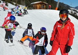 A ski instructor with a group of kids during kids ski lessons for advanced skiers with ski school Jochberg.
