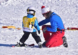 Un moniteur aide un enfant pendant les cours particuliers de ski pour enfants de tous niveaux à Jochberg avec l'école de ski de Jochberg.