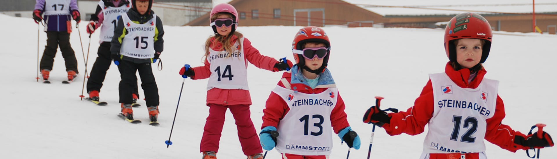 Eine Gruppe Kinder fährt in einer Linie ski beim Kinder-Skikurs “Kids Club” (4-16 J.) für Anfänger mit Skischule Ski Total Kirchdorf.