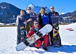 Fünf Snowboarder lacheln in die Kamera wärhend ihrem Privaten Snowboardkurs für Anfänger mit Skischule Ski Total Kirchdorf.