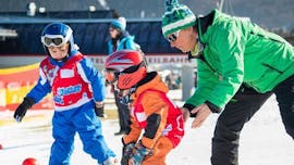Ein kleiner Junge macht im Rahmen des Kurses Kinder Skikurs (4-12 J.) - Alle Levels - Halbtags unter der Aufsicht einer Skilehrerin der Skischule Snow & Bike Factory Willinge die ersten Schritte auf den Skiern.