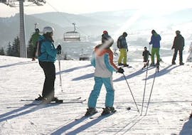 During the Ski Lessons for Teens (13-17 y.)  for All Levels - Half Day, a group of skiers is learning how to ski under the guidance of a ski instructor from Skischule Snow & Bike Factory Willingen.