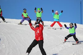 Un gruppo di bambini sta imparando a sciare in discesa con il proprio maestro di sci della Schweizer Skischule Zweisimmen durante le lezioni di sci per bambini (3-16 anni) per principianti.