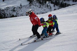 Les enfants apprennent à skier en chasse-neige pendant les cours de ski enfants pour débutants avec l'école suise de ski Zweisimmen.