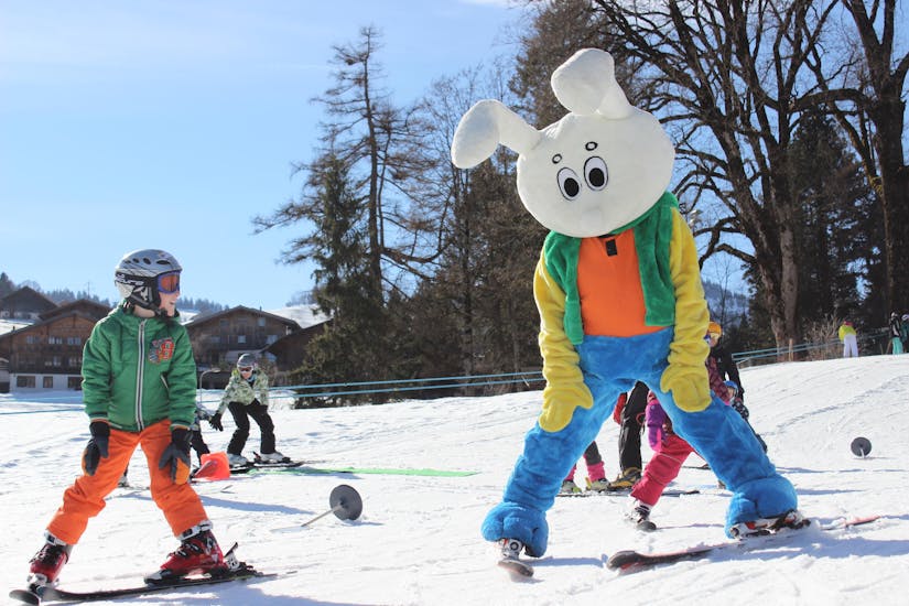 La mascotte de l'école suisse de ski Zweisimmen aide les petits enfants à apprendre le chasse-neige.