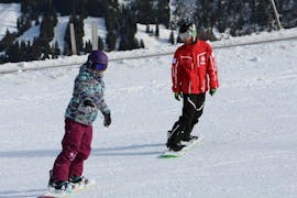 Une fille apprend à faire ses premiers virages sur le snowboard pendant des cours particuliers de snowboard pour enfants et adultes de tous niveaux avec l'école suisse de ski Zweisimmen.