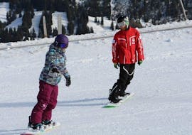 Una ragazza sta imparando le sue prime curve sullo snowboard durante le lezioni private di snowboard per bambini e adulti di tutti i livelli con la Scuola Svizzera di Sci Zweisimmen.