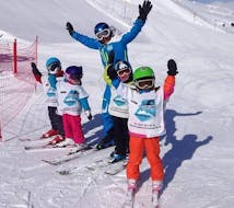 Un gruppo di bambini si diverte sulla neve con il loro istruttore della scuola di sci Silvaplana Top Snowsports durante le lezioni di sci per bambini a tutti i livelli.