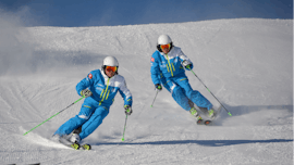 Zwei Skifahrer fahren während dem privaten Kinder-Skikurs mit der Skischule Silvaplana Top Snowsports die Piste hinunter.