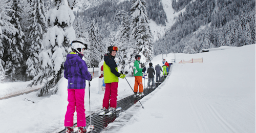 Skilessen voor Kinderen (4-14 jaar) voor Beginners met Skischool Dachstein West Een groep kinderen op een tovertapijt tijdens hun skiles voor kinderen voor beginners bij Skischool Dachstein West in Gossau.