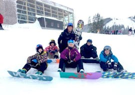Kinderen zitten met hun snowboard in de sneeuw tijdens hun privé snowboardlessen voor kinderen & volwassenen bij de skischool Zell am See Outdo.