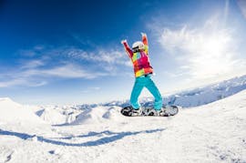 Ein Kind springt beim Snowboardunterricht für Fortgeschrittene mit der Skischule Dachstein West in Gosau in die Luft.