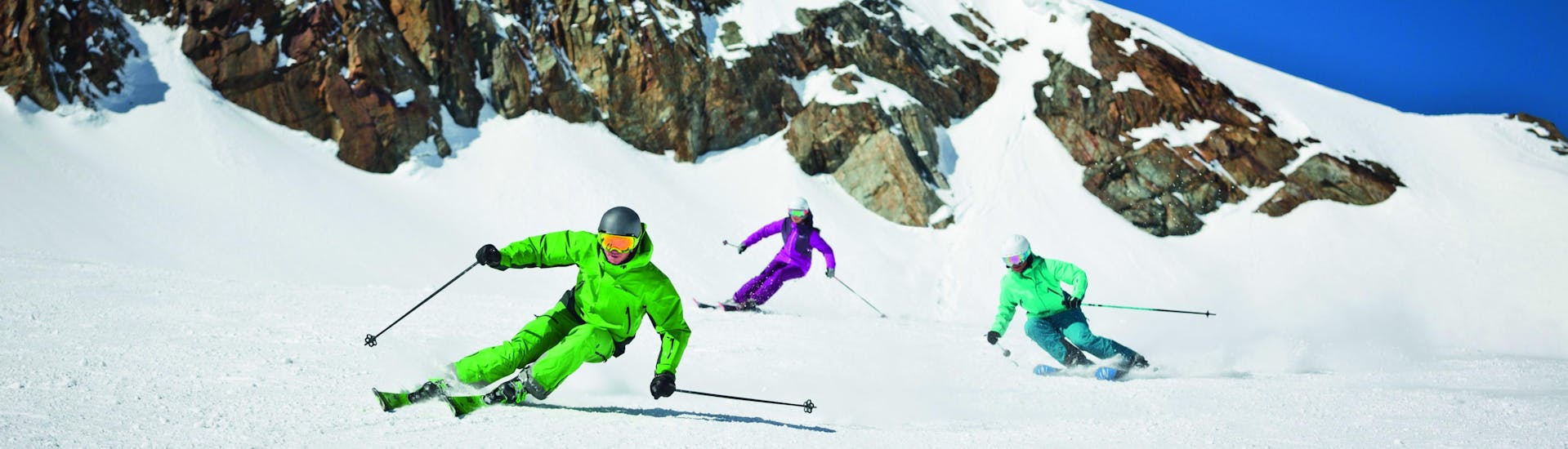 Privater Skikurs für Erwachsene aller Levels mit Skischule Dachstein West Drei Skifahrer fahren während ihres privaten Skikurses für Erwachsene aller Könnerstufen bei der Skischule Dachstein West in Gosau einen Hang hinunter.