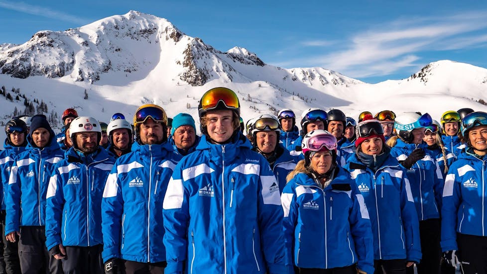 Die Skilehrer der Skischule Fieberbrunn Widmann Mountain Sports die unter anderem auch den Skikurs für Erwachsene - Fortgeschritten unterrichten, posieren gemeinsam für ein Gruppenfoto.