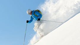 Ein Skifahrer fährt im Rahmen des Angebots "Privater Freeride Kurs - Alle Levels" der Skischule Widmann Mountain Sports im Tiefschnee in Richtung Tal während der Schnee aufgewirbelt wird.
