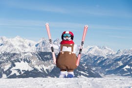 Ein Skimaskottchen steht während des Kinder-Skikurses "Valles" für Anfänger der Skischule Wilder Kaiser in St. Johann auf dem Gipfel eines Berges.