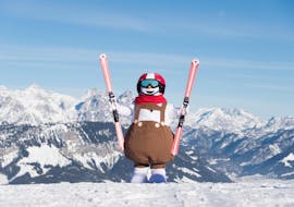 A ski mascot standing on top of a mountain during kids ski lessons "Valles" for beginners with ski school Wilder Kaiser in St. Johann.