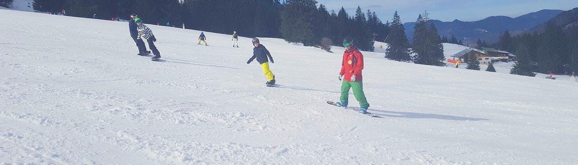 Ein Snowboarder hat beim Snowboardkurs für Kinder für Anfänger in der Skischule Bayrischzell gerade gelernt, wie man eine Kurve fährt.