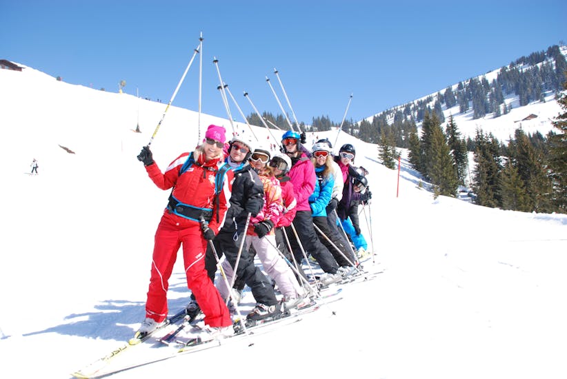Eine Gruppe erwachsener Skifahrer steht in einer Reihe während ihres Skikurses für Fortgeschrittene in der Skischule Heugenhauser Saalbach.