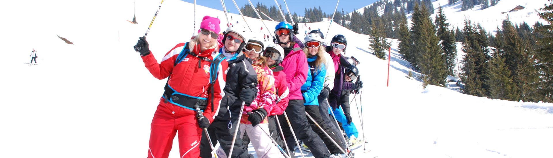 Eine Gruppe erwachsener Skifahrer steht in einer Reihe während ihres Skikurses für Fortgeschrittene in der Skischule Heugenhauser Saalbach.