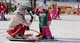 Ein Skilehrer gibt einem Kind während des Kinderskikurses "Bambini" für alle Könnerstufen mit der Skischule Ramsau ein High-Five.