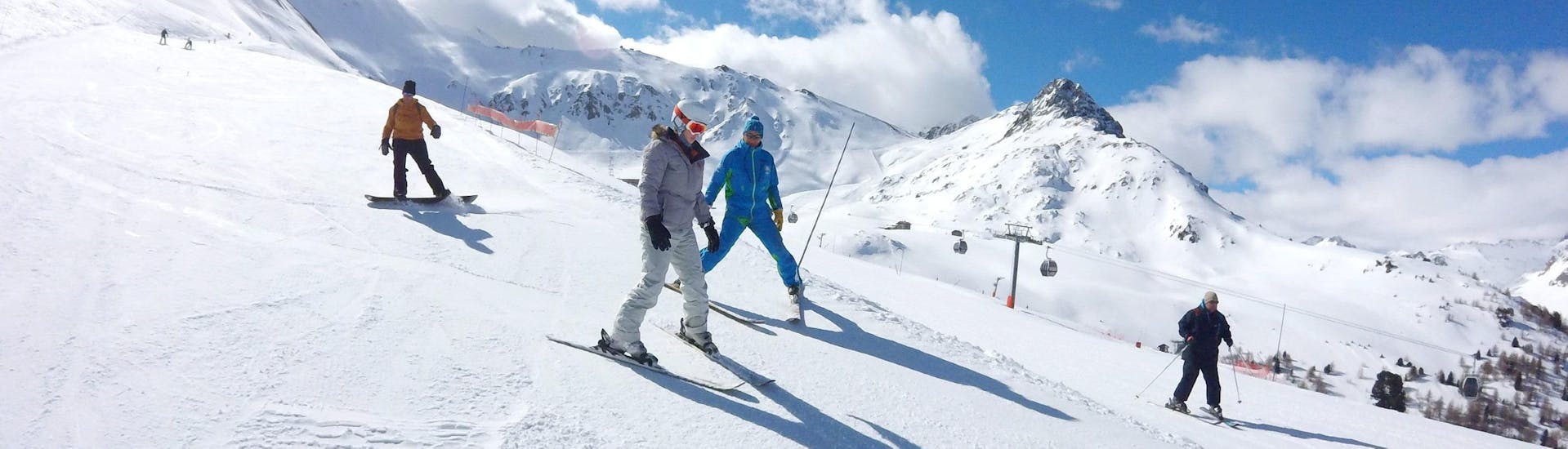 Eine Skifahrerin lernt dank der Hilfe ihres Skilehrers von der Skischule ESI Valfréjus während ihres Privatskikurses für Erwachsene das Skifahren - Alle Levels.