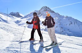Uno sciatore e il suo maestro di sci della scuola di sci ESI Valfréjus si trovano davanti a un paesaggio di montagne innevate durante le lezioni private di sci per adulti - tutti i livelli.