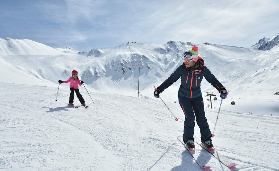 Een jonge skiër volgt hun instructeur van de skischool ESI Valfréjus op een besneeuwde piste tijdens hun Privé Skilessen voor Kinderen - Alle Leeftijden. 
