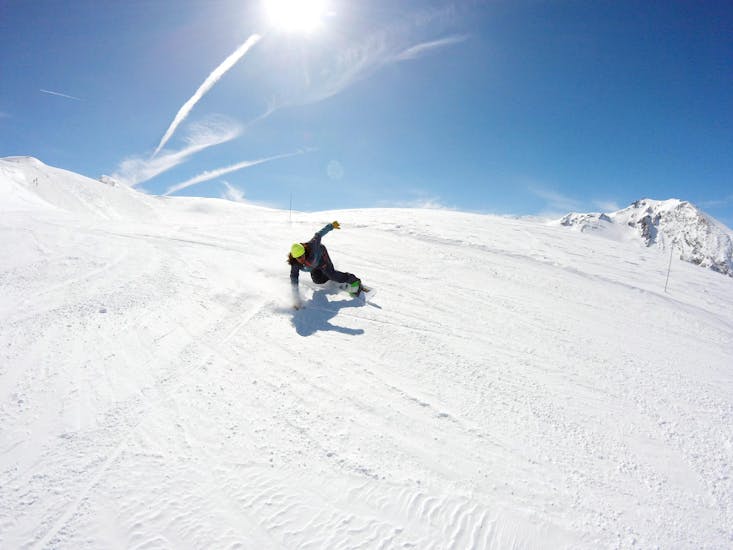 Ein Snowboarder rutscht einen verschneiten Hang hinunter, während er bei der Skischule ESI Valfréjus Privatunterricht im Snowboarden nimmt - alle Levels und Altersgruppen.