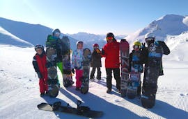 Snowboarder con il loro maestro di snowboard della scuola di sci ESI Valfréjus posano per una foto al termine delle lezioni di snowboard per bambini e adulti - tutti i livelli.