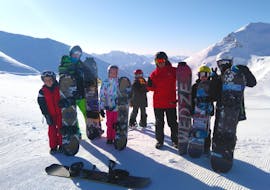 Snowboarders met hun snowboardleraar van de skischool ESI Valfréjus poseren voor een foto aan het einde van hun snowboardles voor kinderen en volwassenen - alle niveaus.