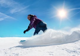 Een snowboarder neemt op een zonnige dag een scherpe bocht tijdens zijn privé-snowboardlessen voor kinderen en volwassenen in Zugspitze met de skischool Skischule Thomas Spenzel.