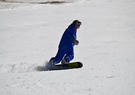 Un snowboarder fait une figure stylée sur les pistes pendant ses cours particuliers de snowboard pour enfants et adultes à Zugspitze avec l'école de ski Skischule Zugspitze-Grainau.