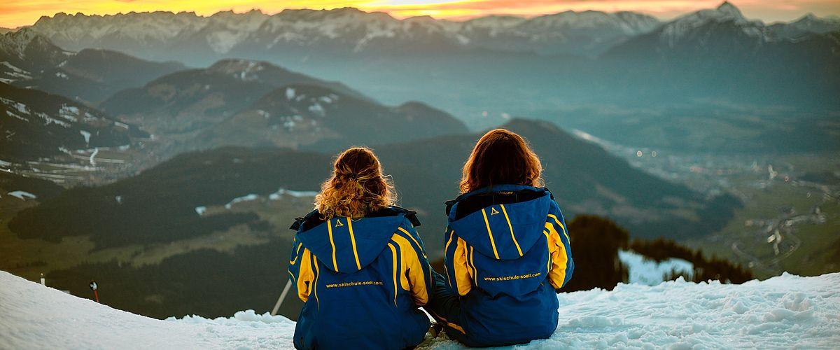 Twee skiërs kijken naar het uitzicht op de bergen tijdens met hun prive-skigids in Söll met skischool Söll Hochsöll Embacher.