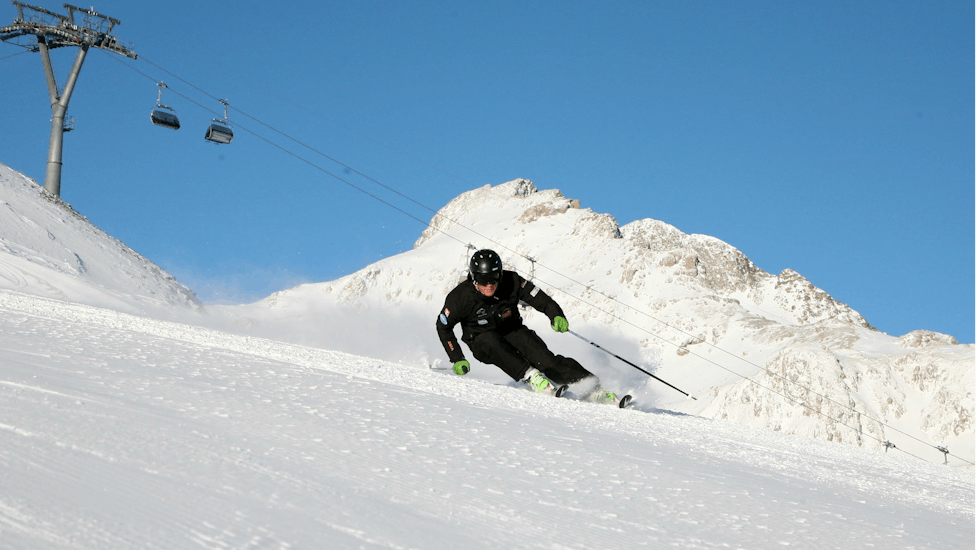 Un skieur dérapes rapidement sur la piste pendant un Cours particulier de ski pour Adultes pour Tous niveaux avec Ski Cool St. Moritz.