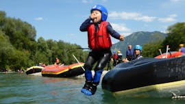 Kid jumping in the river from the rafting boat on a rafting tour on the Iller River in Allgäu with Spirits of Nature Allgäu.
